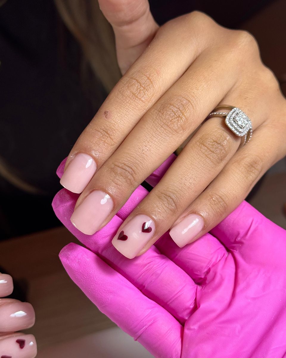 Nude-Maniküre mit kleinen roten Herzen als Nail Art